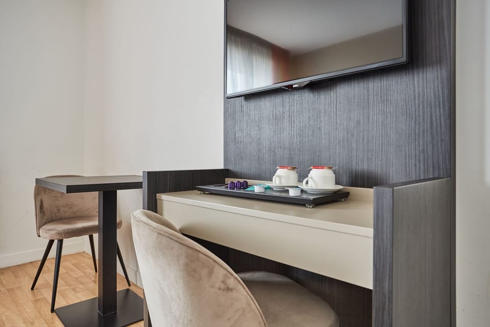 This close-up view highlights a minimalistic workspace with soft seating, featuring a stylish table, decorative tea sets, and a wall-mounted TV that enhances the contemporary decor.