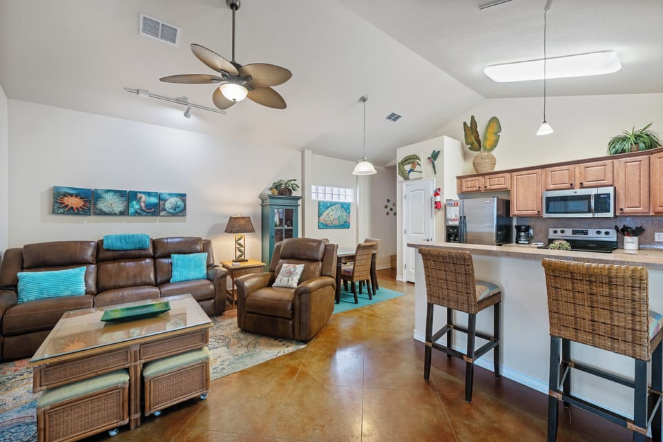 Relax in your bright, open-concept living space featuring comfortable leather seating and a fully equipped kitchen for memorable meals together.
