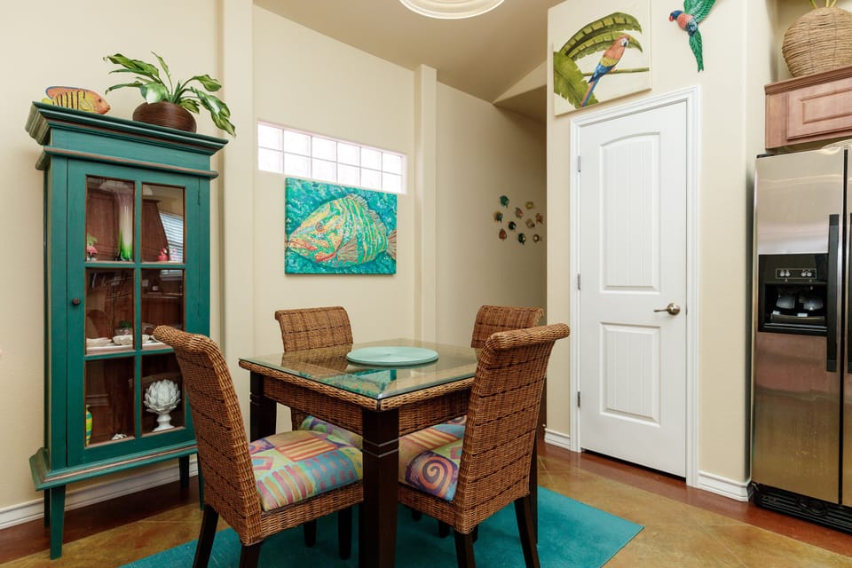 Your tropical-themed dining nook welcomes you with wicker chairs and vibrant artwork, perfect for morning coffee or intimate meals together.