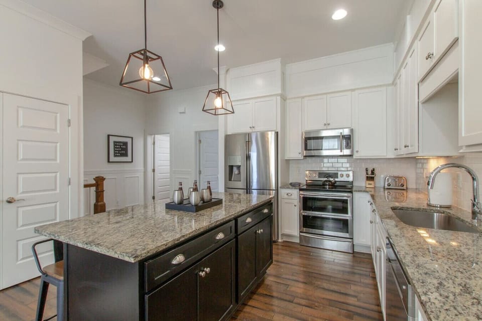 A spacious and modern kitchen with an island, stainless appliances, and warm pendant lighting.