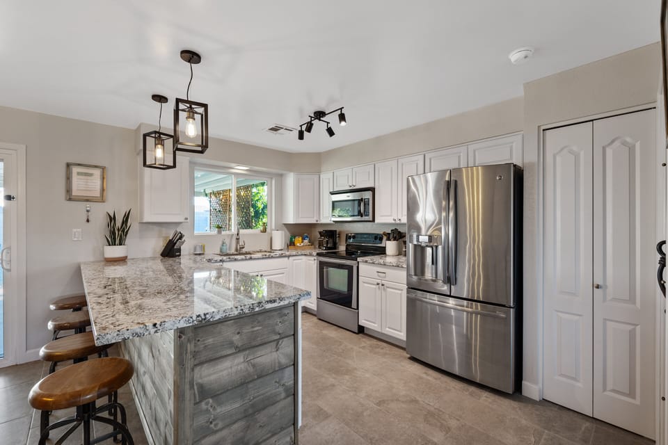 Spacious kitchen with large countertop and 4 barstools.