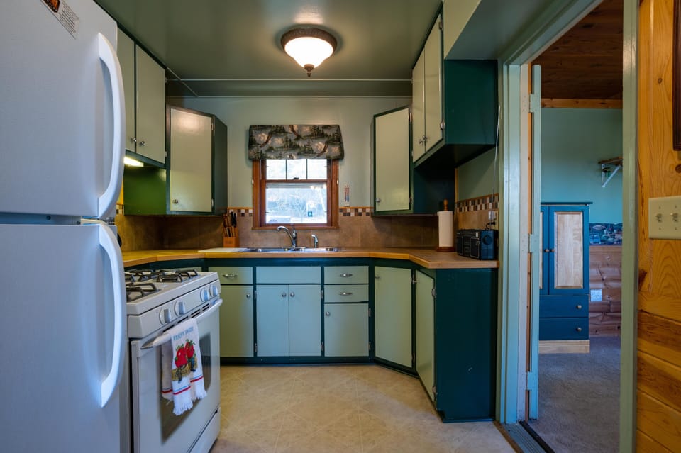 kitchen with full-sized fridge, gas stove/oven, and door to bedroom 3