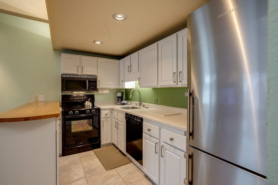 Your fully equipped kitchen awaits with stainless steel appliances, white cabinets, and a charming breakfast bar for your morning coffee.