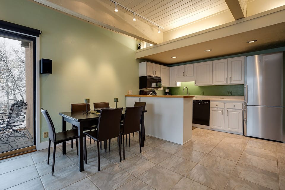 Step into your modern kitchen-dining space with sleek appliances, warm wood accents, and bright natural light streaming through patio doors.