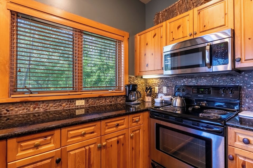 Your fully equipped kitchen features warm wood cabinets, stone backsplash, and modern appliances for creating memorable meals during your stay.