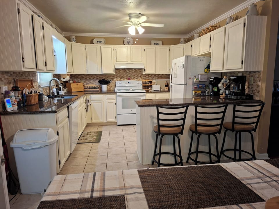 Large kitchen with granite countertop, full-size appliances, and island seating.