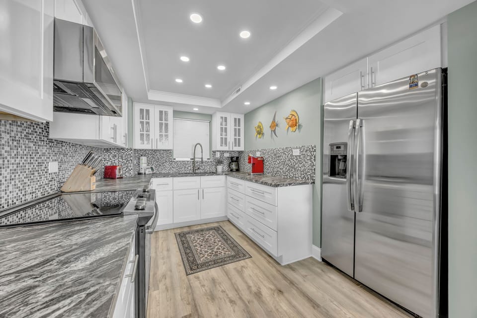 Your culinary haven awaits with gleaming marble countertops, modern stainless appliances, and a stylish mosaic backsplash that catches the light beautifully.