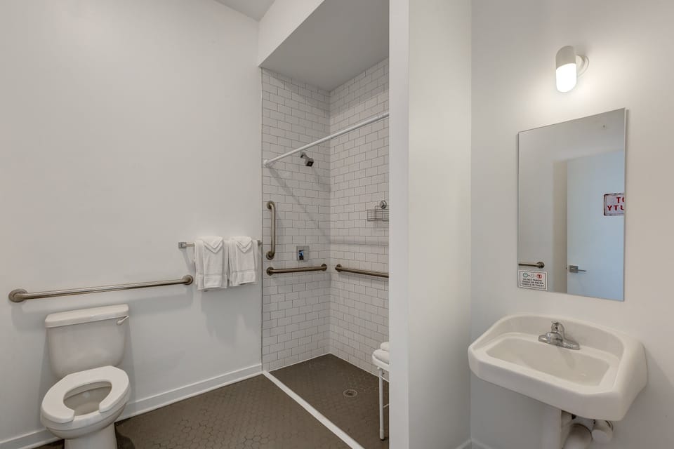 Note the step-free shower, grab bars, and open space below the sink