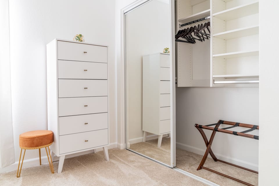 Every bedroom includes a dresser, luggage stand, and wooden hangers.