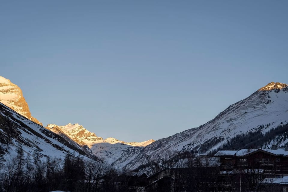 Snow-capped Alpine peaks bathed in warm golden light at dusk.