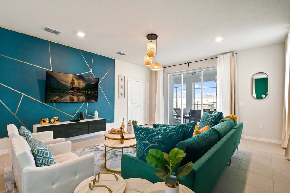 Chic designer living room with bold teal accents and seamless poolside access.