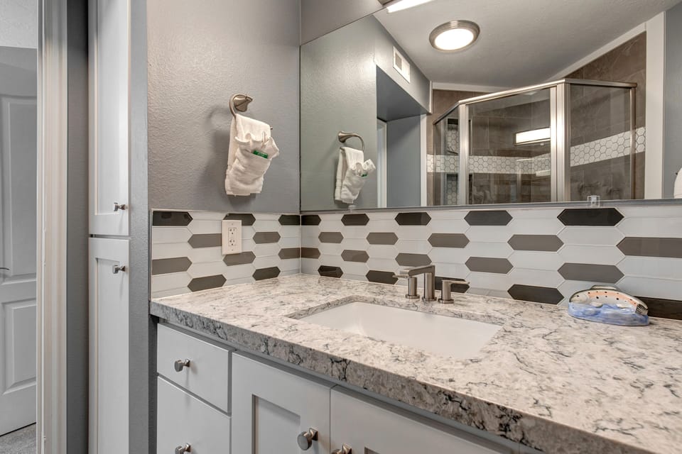 Start your day refreshed in your private bathroom with elegant granite countertops, modern geometric tile work, and plush towels waiting for you.