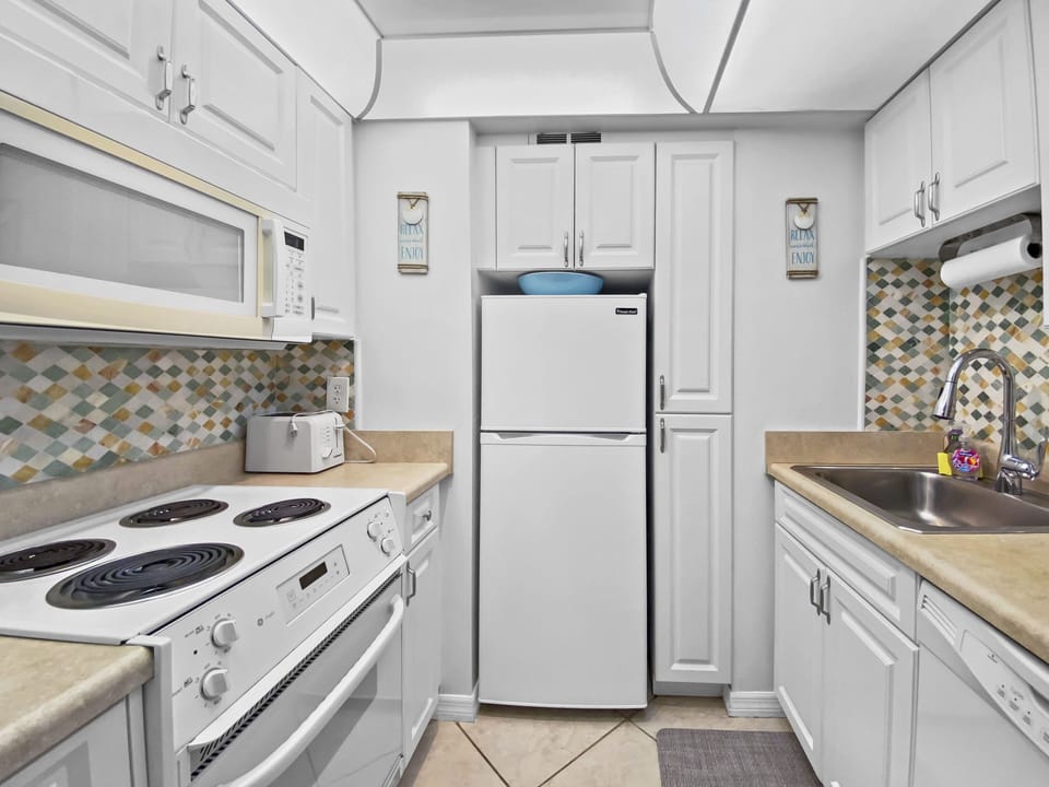 Kitchen with white shaker cabinets, mosaic tile backsplash, white appliances, and tile flooring