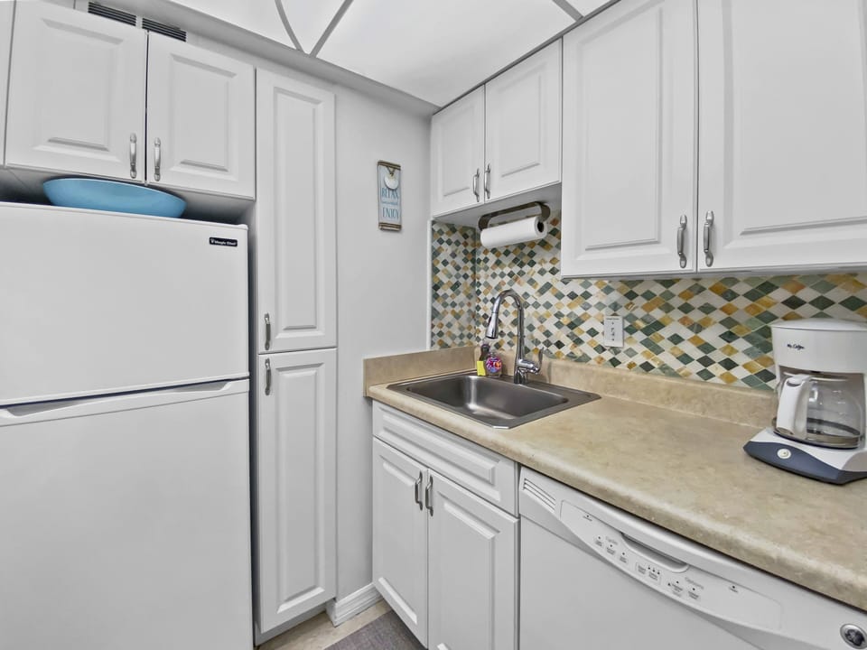 Kitchen featuring mosaic backsplash, white refrigerator, stove, and sink area with ample counter space