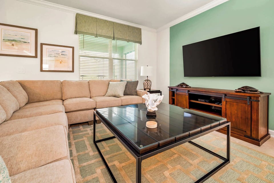 Relax in this elegant living room with a cozy sectional, large TV, and stylish decor, perfect for unwinding after a day of adventure.