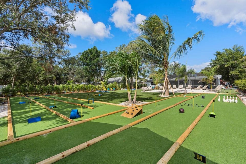 Mini golf course with bamboo hole obstacles, colorful flags, palm trees and screened pool in background, near Universal Orlando