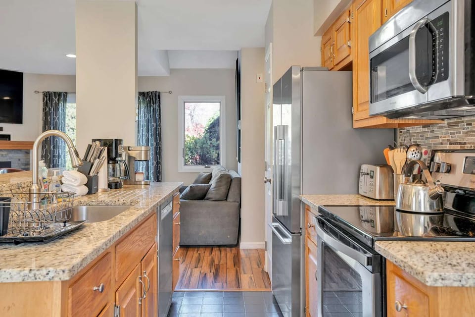 Well-equipped kitchen with granite countertops, stainless steel appliances, and mosaic backsplash