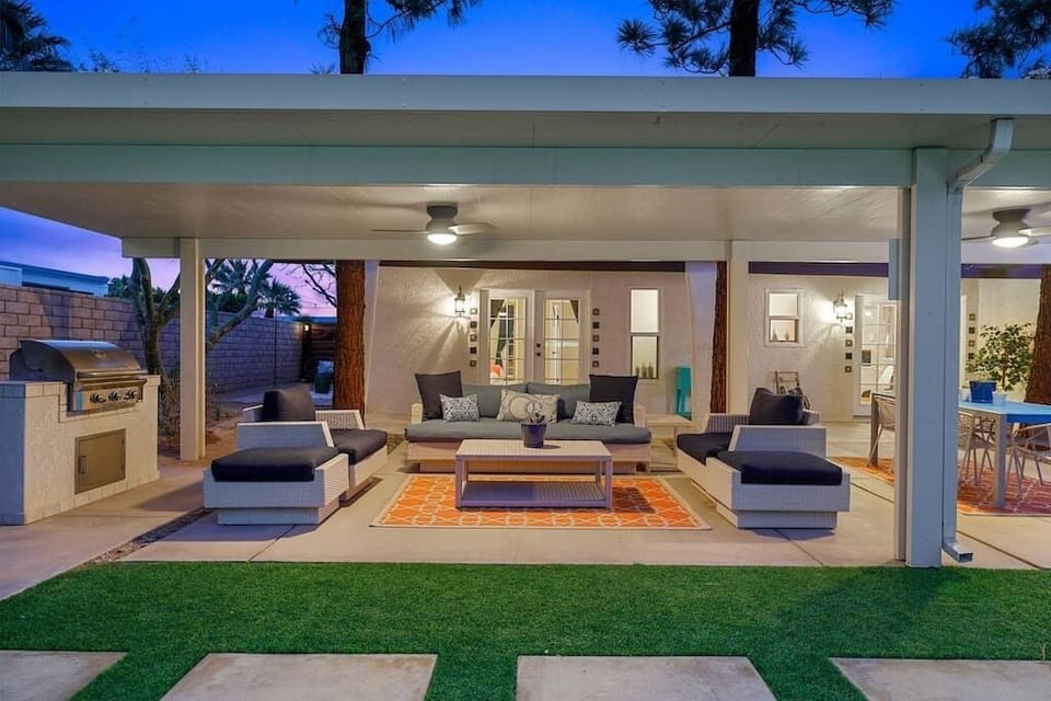 Twilight covered lounge with wicker sectional, ceiling fans, built-in gas grill & dining area — the backyard room that runs all night.