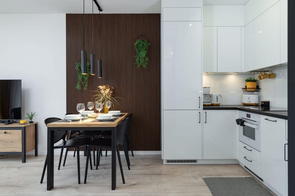 A dining area adjacent to a sleek white kitchen with modern appliances.





