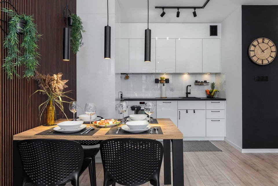 A bright and clean kitchen with white cabinets and black countertops.
