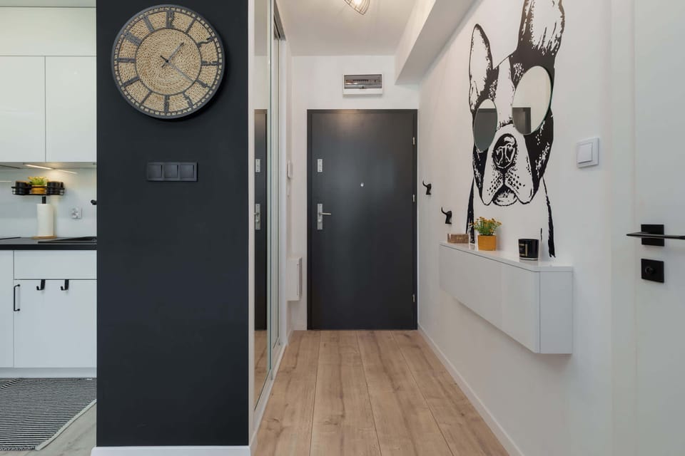 A hallway with a clock and modern wall art leading to other rooms.
