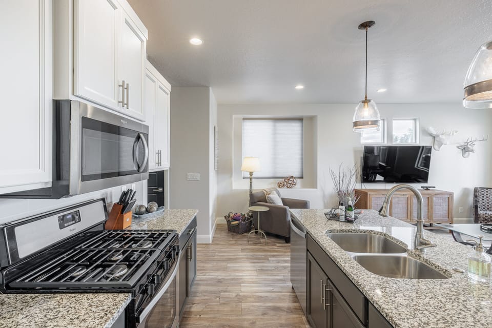 Kitchen Side View - The kitchen is fully stocked with all the dishes, cookware, baking pans, and cutlery you will need for meal preparations and includes stainless steel appliances and granite counter tops.
