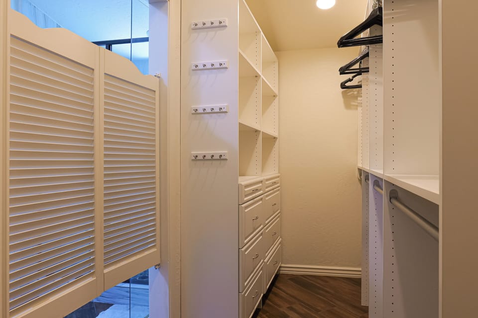 Large walk-in closet with wooden hangers and built-in drawers. (Bathroom 4)
