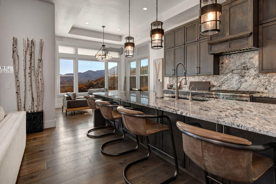 Gather at the kitchen island with views of the surrounding mountains. Enjoy preparing meals together and relaxing in this beautiful space with natural light streaming through large windows.