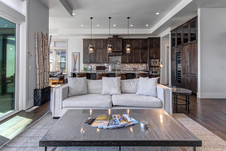Sink into plush seating and enjoy the open flow between your living space and gourmet kitchen, where rich wood tones and elegant pendant lighting create a warm, inviting atmosphere perfect for relaxing or entertaining.