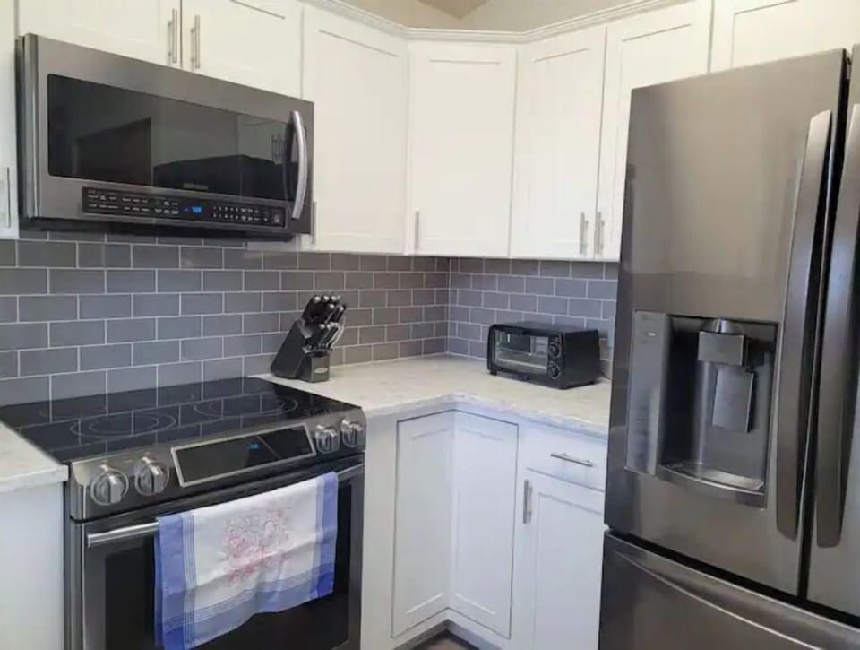 Kitchen includes microwave, range, toaster oven, and fridge with ice maker. 