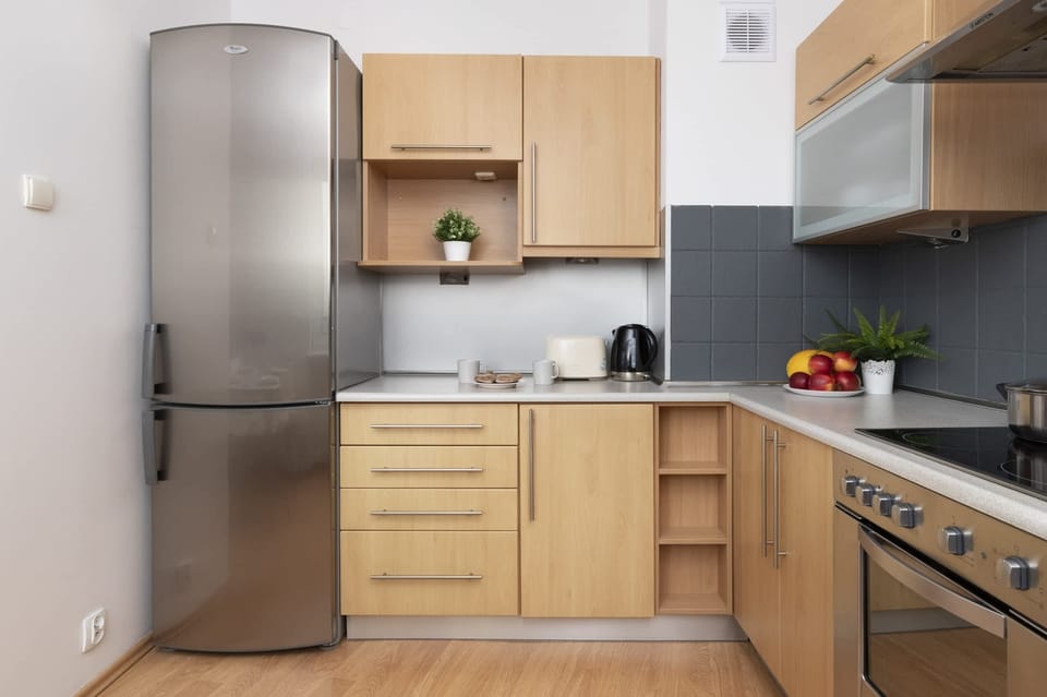 A compact kitchen with wooden cabinets, a refrigerator, and a modern design.
