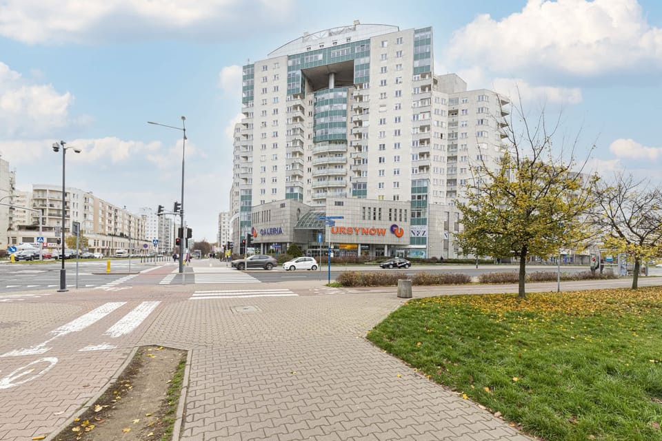 An exterior street view of a modern residential building with pathways and greenery.





