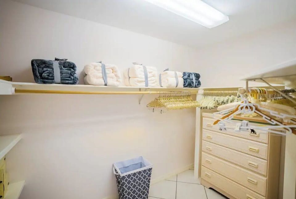Master bedroom walk-in closet with blankets, a safe, a high chair and iron board