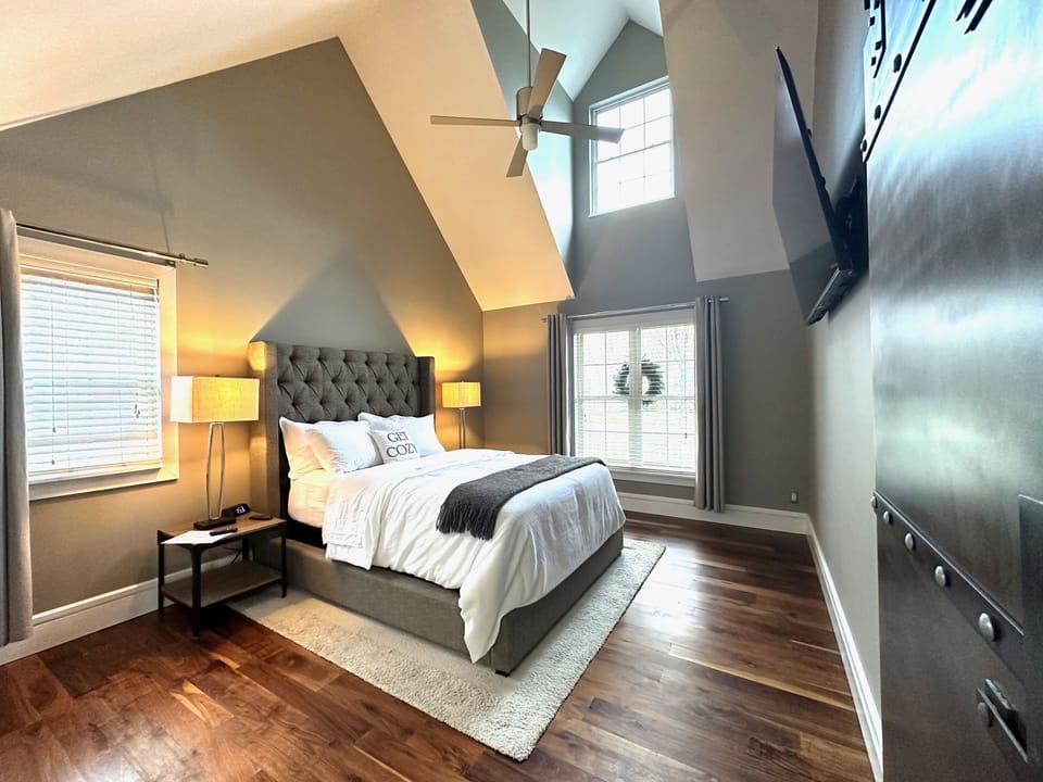Primary bedroom on 1st floor w/ ceiling fan and 65" smart tv.