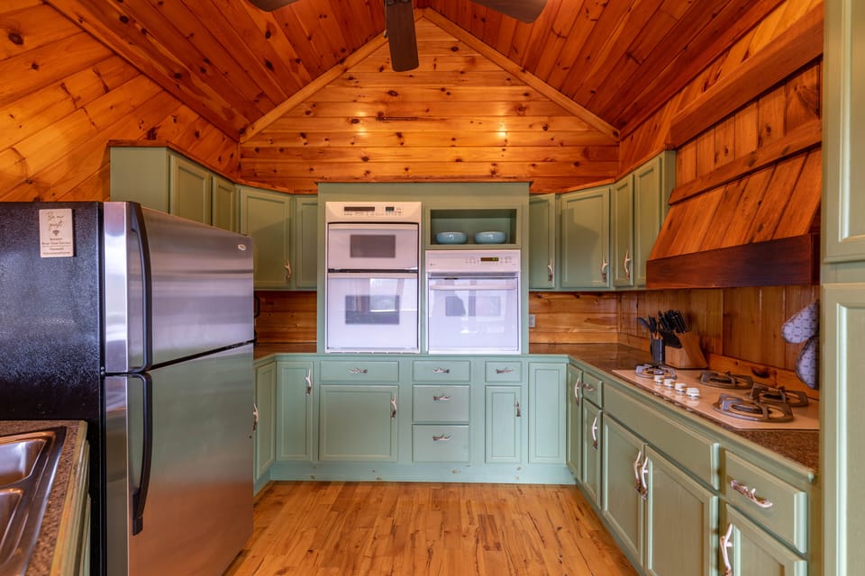 Fully equipped and full of mountain charm. The sage green cabinetry and soaring knotty pine ceiling make cooking feel like part of the getaway.
