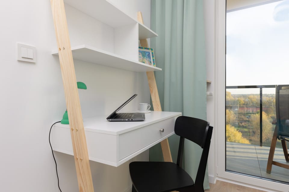 A corner workspace in the bedroom with a desk, chair, and shelves, ideal for working or studying.