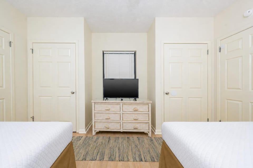 Relax in this inviting guest room featuring two double beds, a TV, and a charming dresser for your convenience