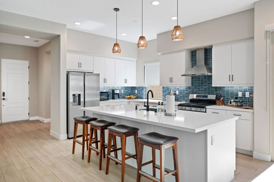 Spacious kitchen island w/ bar seating & pendant lighting overhead.