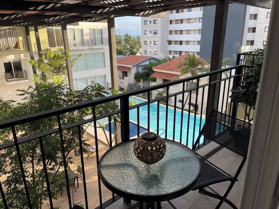 Small balcony overlooking the pool and a peek a boo of the ocean. small table and 2 chairs