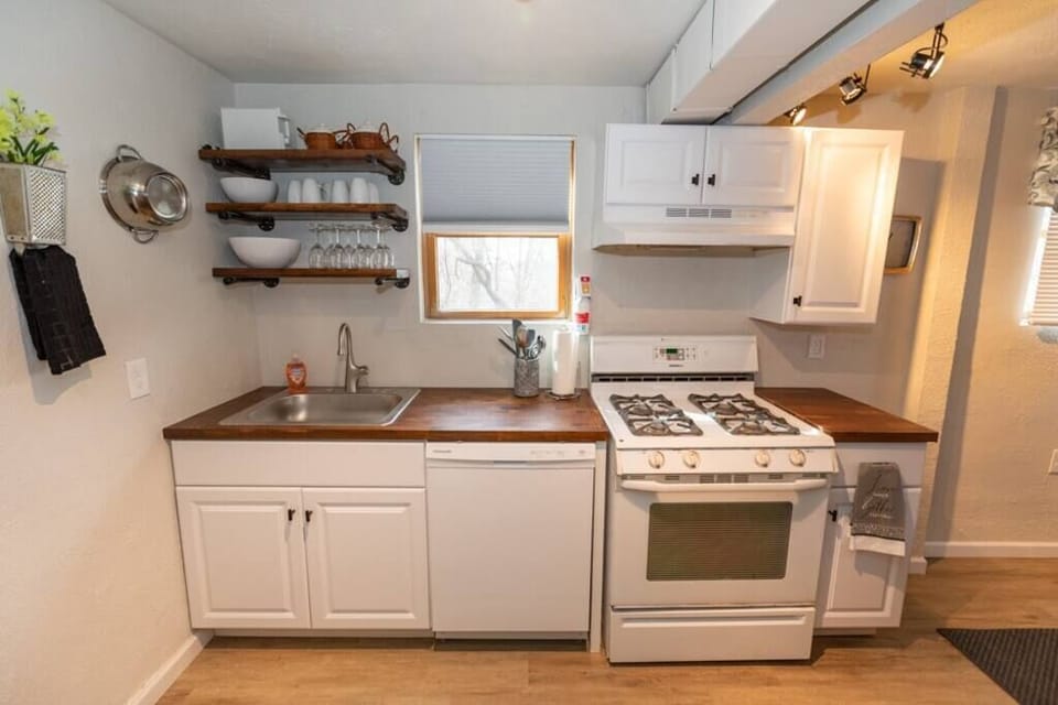 Fully stocked kitchen, with range, dishwasher, dishware, and awesome open shelves