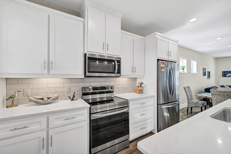 Fully equipped coastal kitchen featuring stainless steel appliances, white cabinetry, and ample prep space.