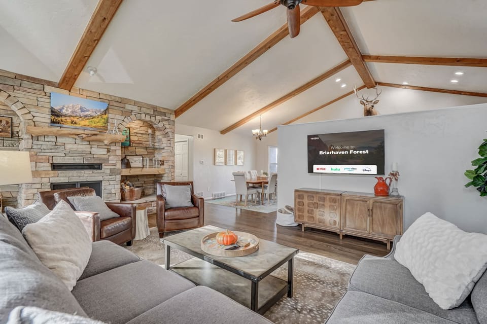 Welcome to Briarhaven Forest! Spacious living room with vaulted ceilings, exposed beams, a cozy stone fireplace, and Smart TV—perfect for relaxing evenings.

