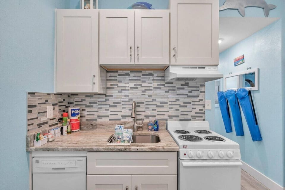 Functional kitchen w/ full-size stove, tiled backsplash, & bright, beachy touches.