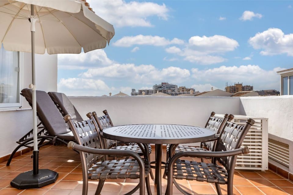 Spacious rooftop terrace with dining set under an umbrella, ideal for al fresco meals with a view.