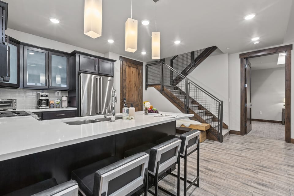 Fully equipped kitchen space features stainless steel Viking appliances, stone countertops, and bar seating for four