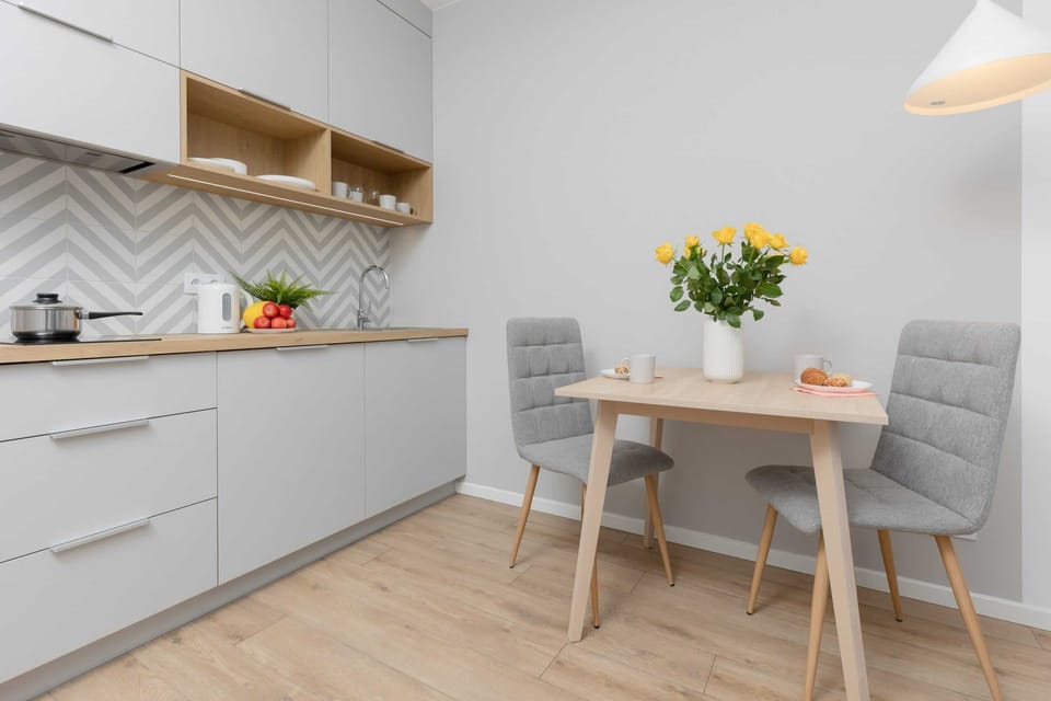 A compact and fully equipped kitchen featuring white cabinets, wooden countertops, and a geometric backsplash. The kitchen includes modern appliances and ample storage.