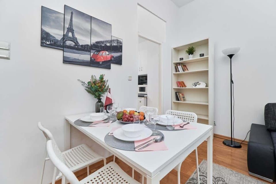 A dining table set for guests, with elegant tableware and a centerpiece of fresh fruit.