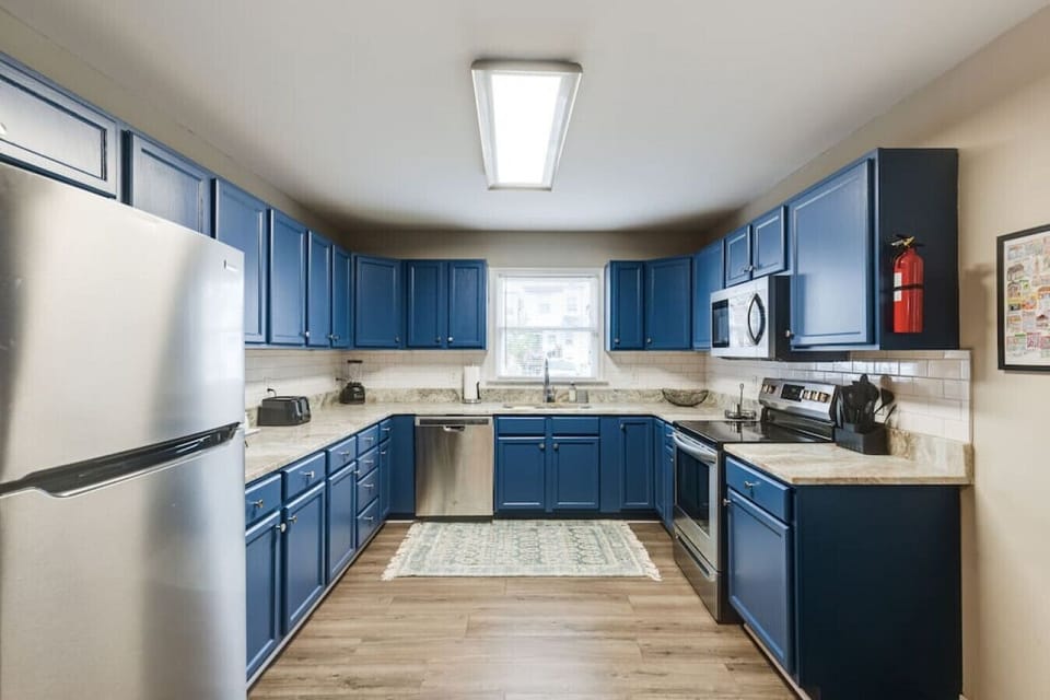 Fully stocked with all your cooking essentials, featuring a microwave, dishwasher, and a double-basin sink with a  window view—everything you need to feel at home.