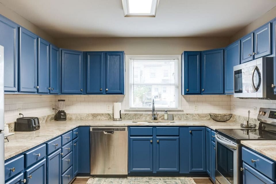 Fully stocked with all your cooking essentials, featuring a microwave, dishwasher, and a double-basin sink with a  window view—everything you need to feel at home.