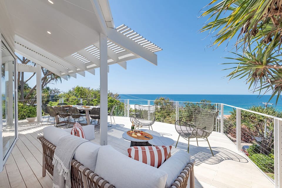 Ocean-view deck has seating, a Weber barbecue, and nearby beach access close by.